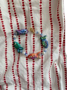 two fish bracelets on a red and white striped tablecloth with polka dot dots