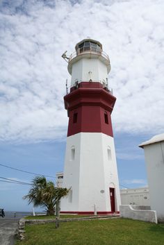 a red and white lighthouse sitting on top of a lush green field