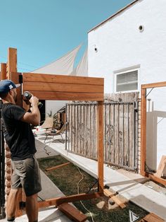 a man holding a camera up to the side of a house