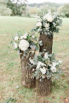 three tree stumps decorated with flowers and greenery for an outdoor wedding or reception