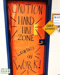 an orange door with writing on it that says caution hard hat zone learning is at work