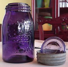 a purple mason jar sitting on top of a table next to a container with something in it