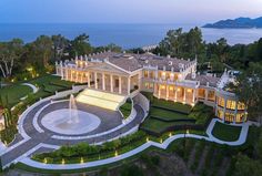 this is an aerial view of a mansion at dusk with the ocean in the background