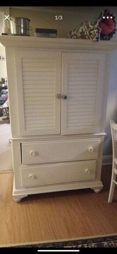 a white armoire with shutters on the doors and drawers in front of it