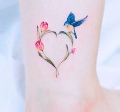 a small heart shaped tattoo with flowers and a bird on the back of its leg