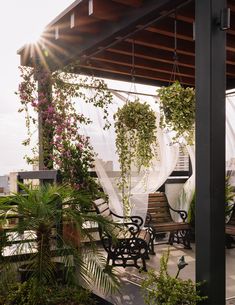 the sun shines brightly on an outdoor patio with chairs and tables covered by plants