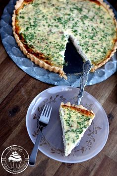 a quiche is on a plate with a fork and knife next to the pie