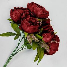 a bouquet of red flowers sitting on top of a white table