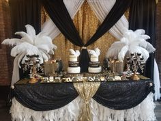 a table topped with cakes covered in white and black feathers