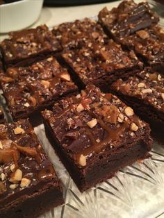 there are many brownies on the glass platter and one is cut into squares