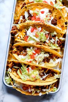 a tray filled with tacos covered in toppings