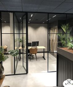 an office with glass walls and plants in the center