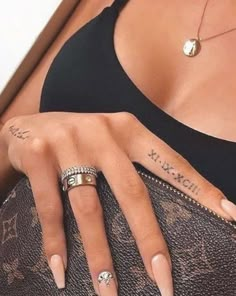 a woman's hand with tattoos on her left arm and two rings in the middle