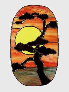 a stained glass window with a tree in the sunset