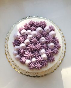 a white cake topped with purple and white frosting flowers on top of a table