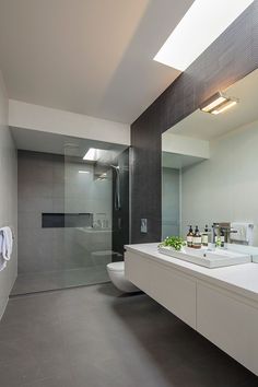 a bathroom with two sinks and a large mirror in the center, along with a skylight above it