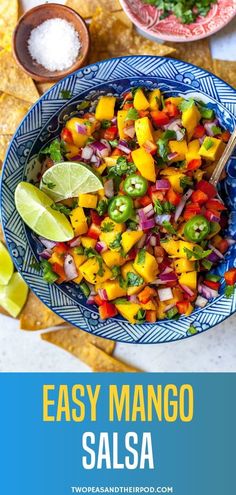 mango salsa in a blue bowl with tortilla chips and limes on the side