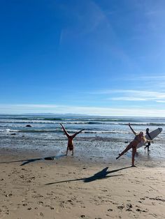 two people doing handstands on the beach with their surfboards in front of them