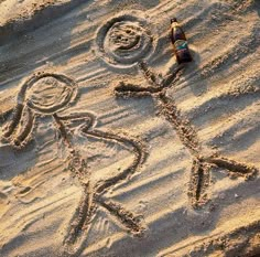 two people are depicted in the sand with one person holding a bottle and another is drawing on it