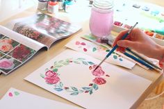 someone is painting flowers on paper with watercolors