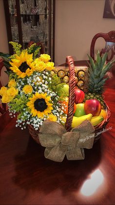 a basket filled with fruit and flowers sitting on top of a wooden dining room table