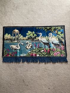 a tapestry hanging on the wall with birds and flowers in front of it, next to a carpeted floor