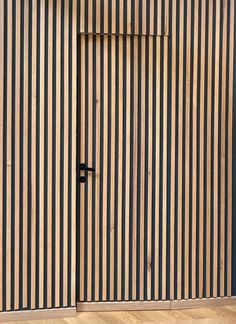 a cat sitting on top of a wooden floor next to a wall with vertical stripes