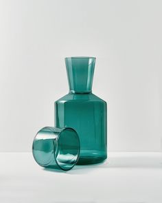 two green vases sitting next to each other on a white surface with no one around them