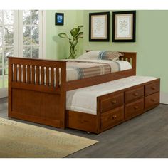 a twin bed with trundle and drawers in a green room next to a window