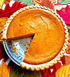 a pie sitting on top of a table with leaves around it and one slice missing