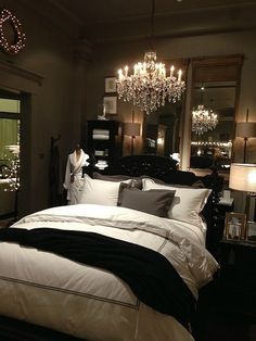 a bedroom with a chandelier hanging from the ceiling and a bed in front of it