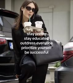 a woman walking down the street carrying a black bag and holding a drink in her hand