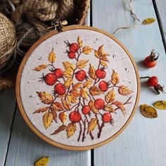 a close up of a embroidery on a wooden surface with other items in the background