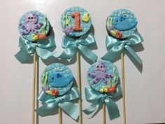 there are four cupcakes on the stick with blue ribbons and sea animals in them