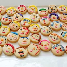 many decorated cookies with faces on them sitting on a white counter top next to each other