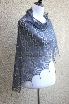 a white mannequin wearing a gray and black shawl on top of a table