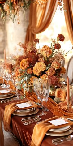 the table is set with orange flowers and place settings