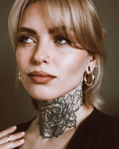 a woman with tattoos on her neck posing for the camera