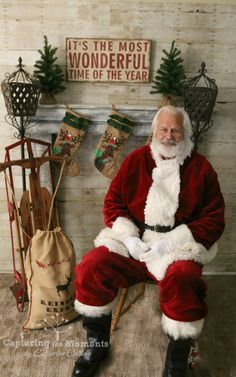 a man dressed as santa claus sitting in front of a fireplace