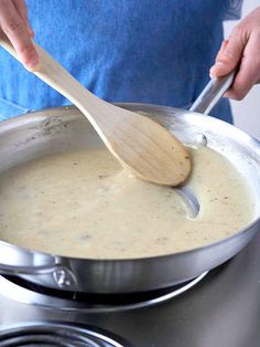 a person is stirring something in a pot on the stove with a wooden spatula