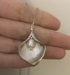 This necklace is made from Silver Plated brass with an AAA quality freshwater pearl. The pendant on the necklace measures 22mm(w) x 32mm(h). The pendant is hung on a rhodium plated chain and you can choose from either 16 or 18 inch chain length. I also sell this necklace as part of a Jewellery set with matching earrings: https://www.etsy.com/uk/listing/400767345/silver-pearl-jewellery-set-calla-lily?ref=shop_home_active_21 Sending as a gift? All my items are sent in a lovely gift box, ready to give as a gift (or just as importantly as a treat for yourself). However if you'd like a personalised handwritten message to be included just send me a note when putting in the order and I will include a little gift card with your message.  I use Royal mail First Class Delivery on UK orders and Inter