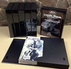 the comic book is on display in front of two black cases and one white box