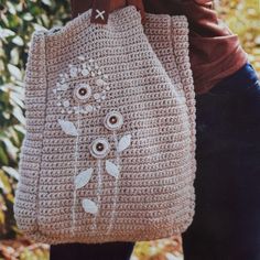 a woman carrying a crocheted bag with flowers on it