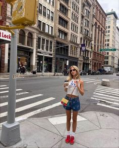 a woman standing on the side of a street next to a traffic light