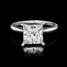 a princess cut diamond ring on a black background