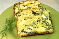 two pieces of bread with cheese and herbs on it sitting on a green plate next to a sprig of dill