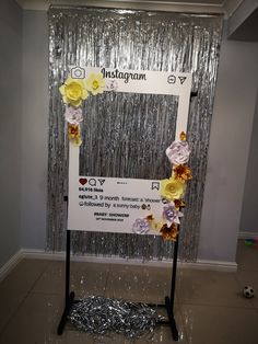 a photo frame decorated with flowers and tinsel on a stand in front of a curtain