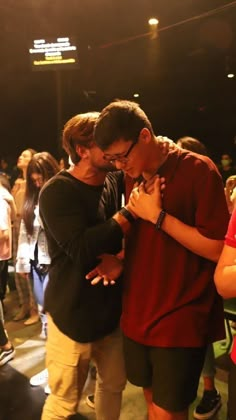 two young men standing next to each other in front of a group of people at a concert