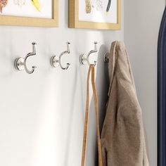 three hooks are hanging on the wall next to a coat rack