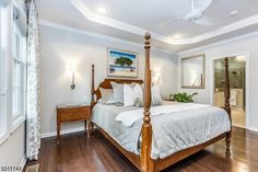 a large bed sitting inside of a bedroom on top of a hard wood flooring